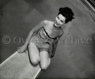 Debra Paget sitting on diving board